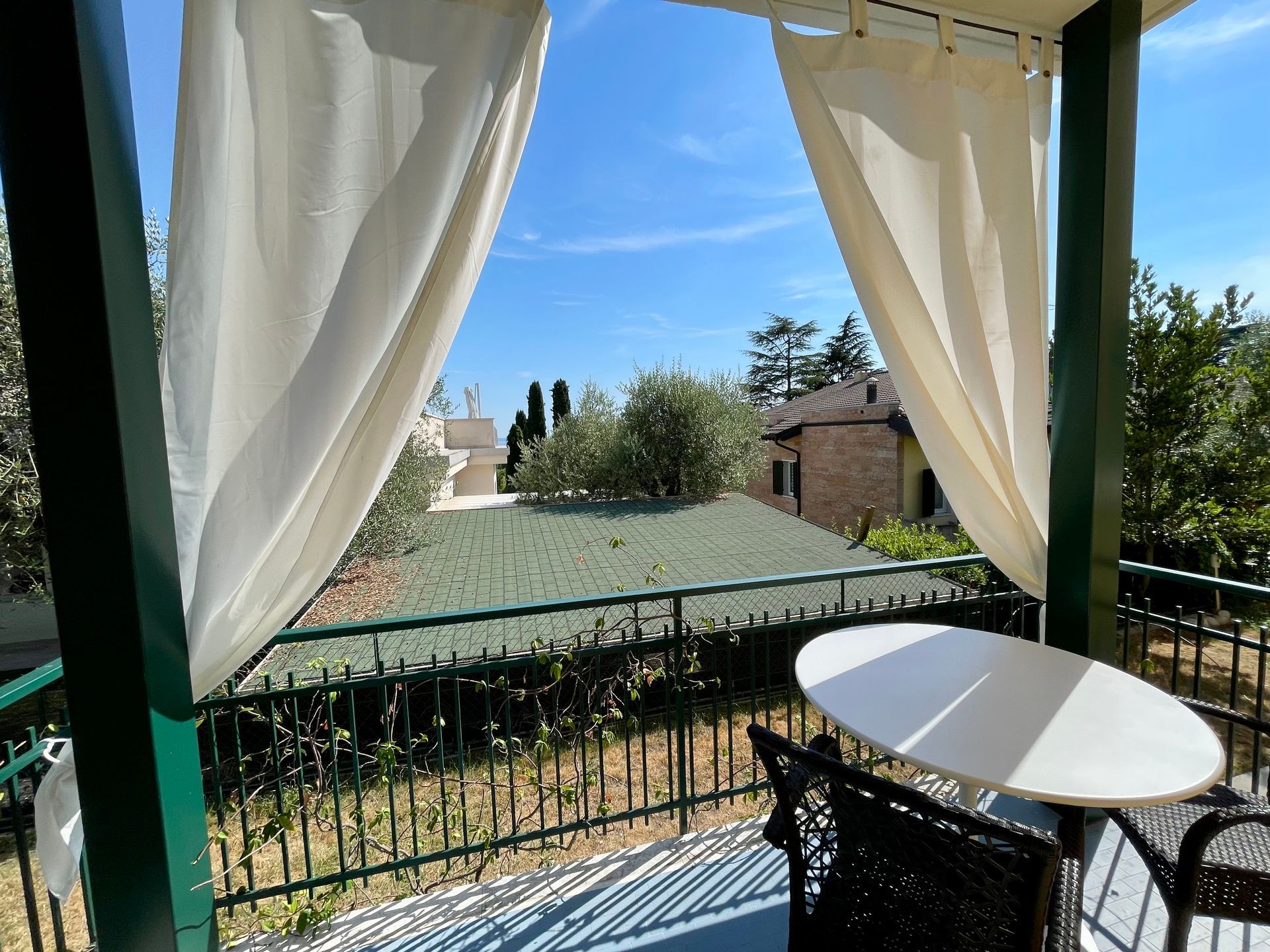 Balcone coperto con tavolo e sedie per pranzare all'esterno e tende per il sole