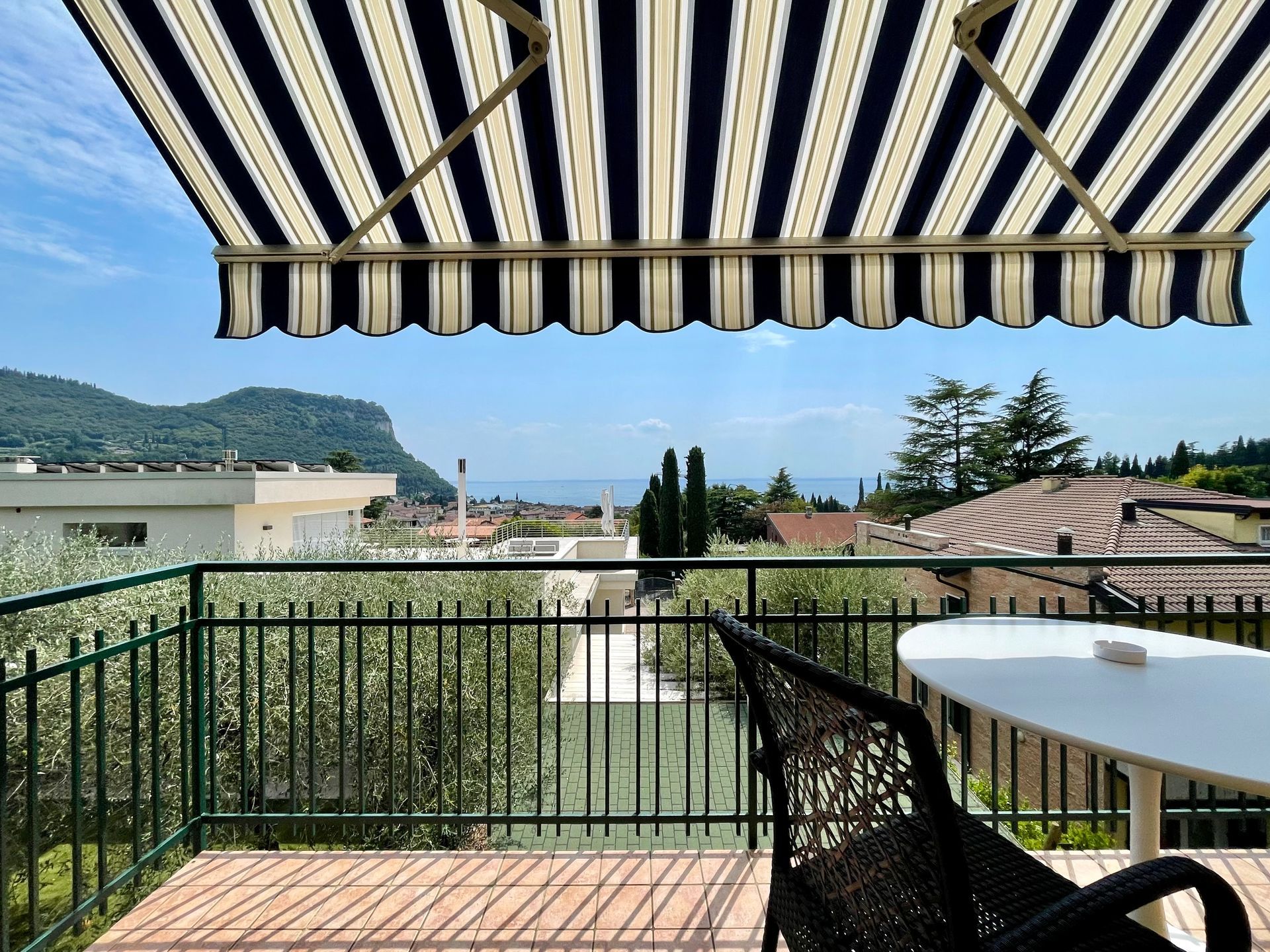 Balcone con splendida vista lago, tenda ombreggiante sopra e tavolo con sedie