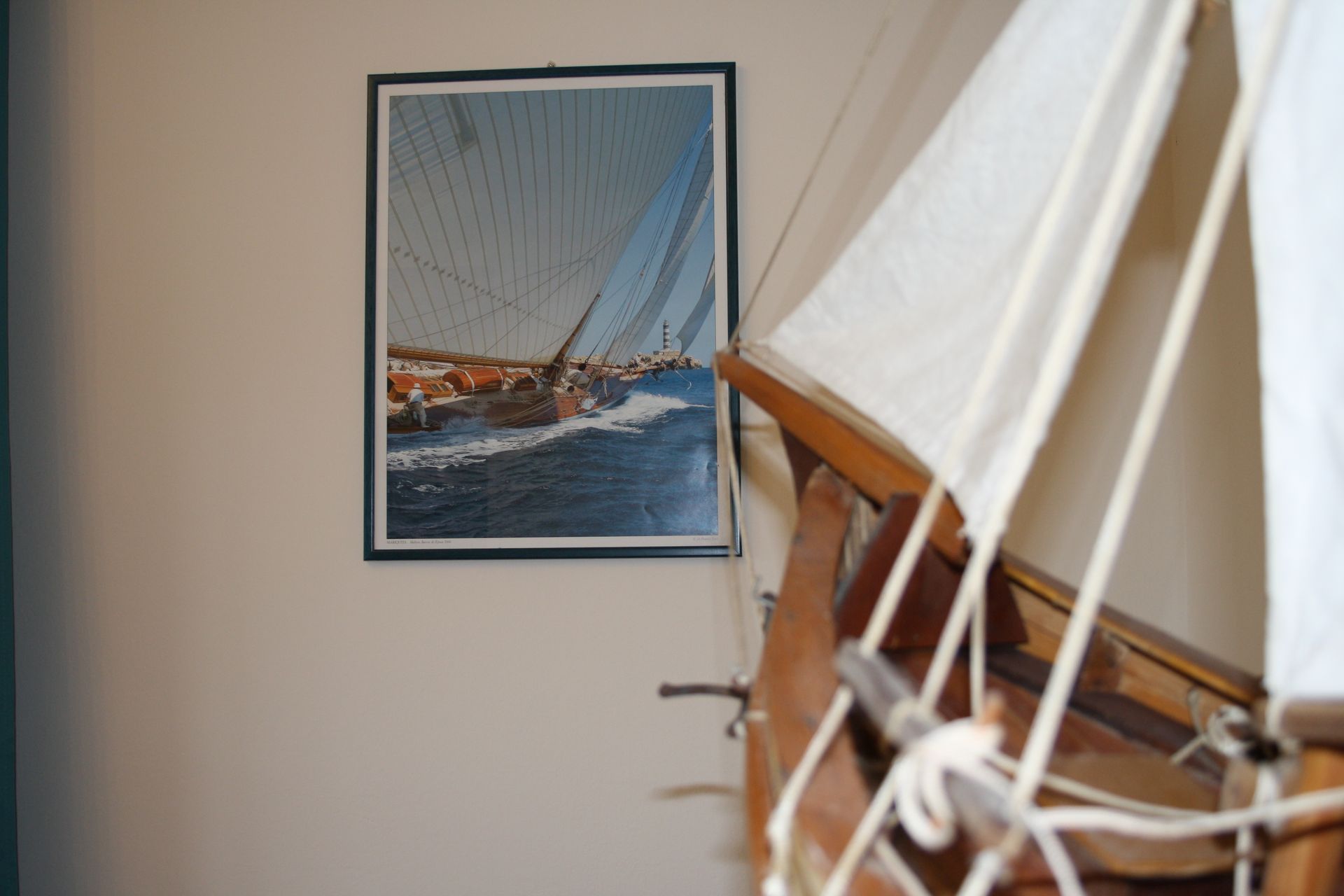 Dettaglio del modellino di veliero in legno con le vele in cotone e quadro con barca a vela
