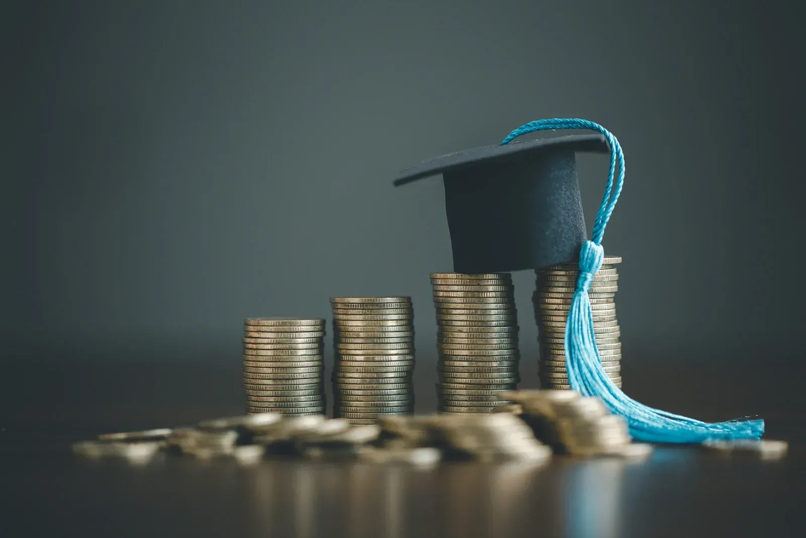 Stacks of coins with a graduation cap on top, symbolizing educational funding.