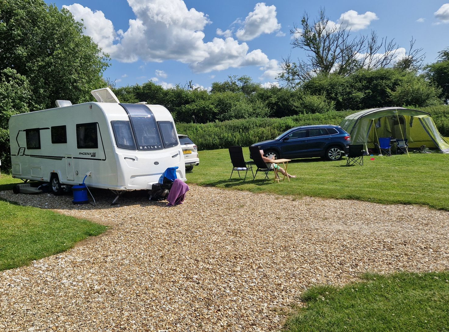 Caravan on hardstanding with tent on a grass pitch in the background