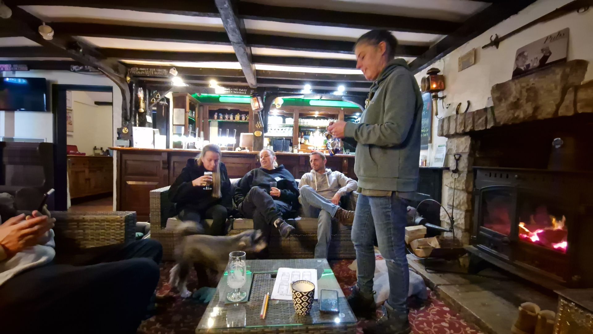 Friends chatting by log burner during private group booking at the Three Horseshoes