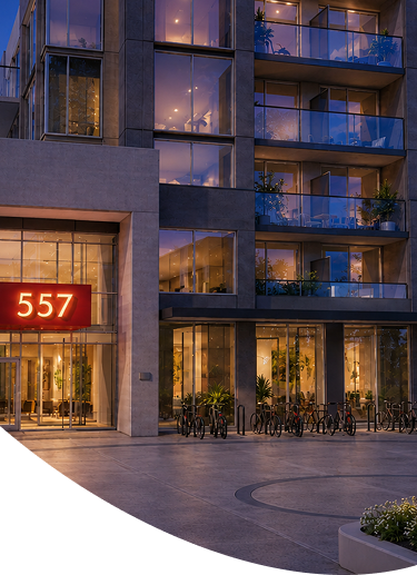 Modern apartment building entrance at dusk with lit balconies and red address sign 557