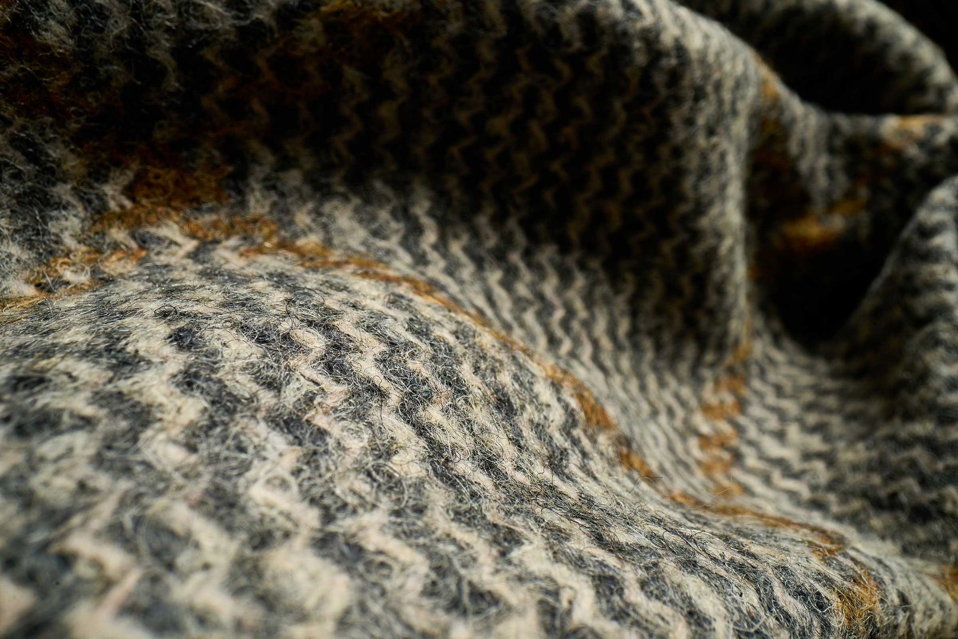 Close-up of textured woven fabric in gray, black, and tan with a soft, rippled pattern