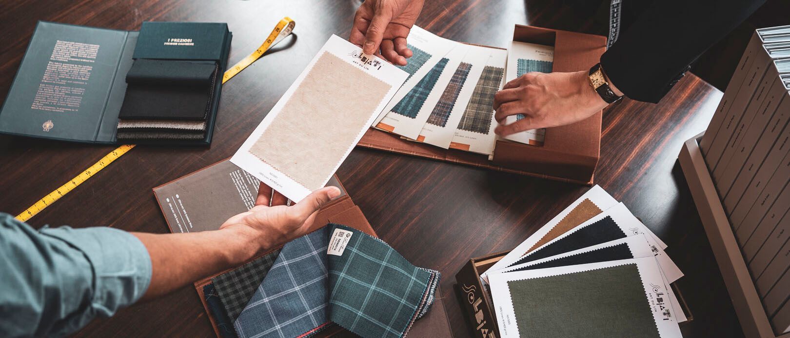 Hands reviewing fabric swatches and color samples on a table in a design meeting