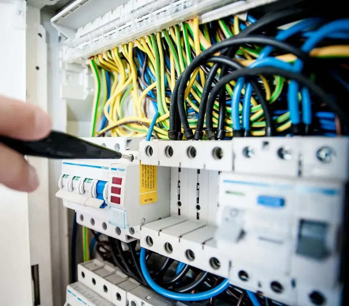 Hand adjusting electrical breakers in a panel with blue, yellow, and black wiring