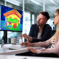 Two people reviewing a colorful thermal image on a monitor in an office