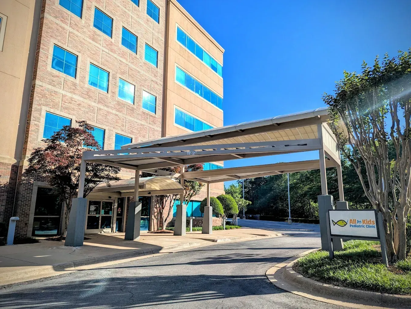 Modern building with blue-tinted windows; covered entrance, sign: 