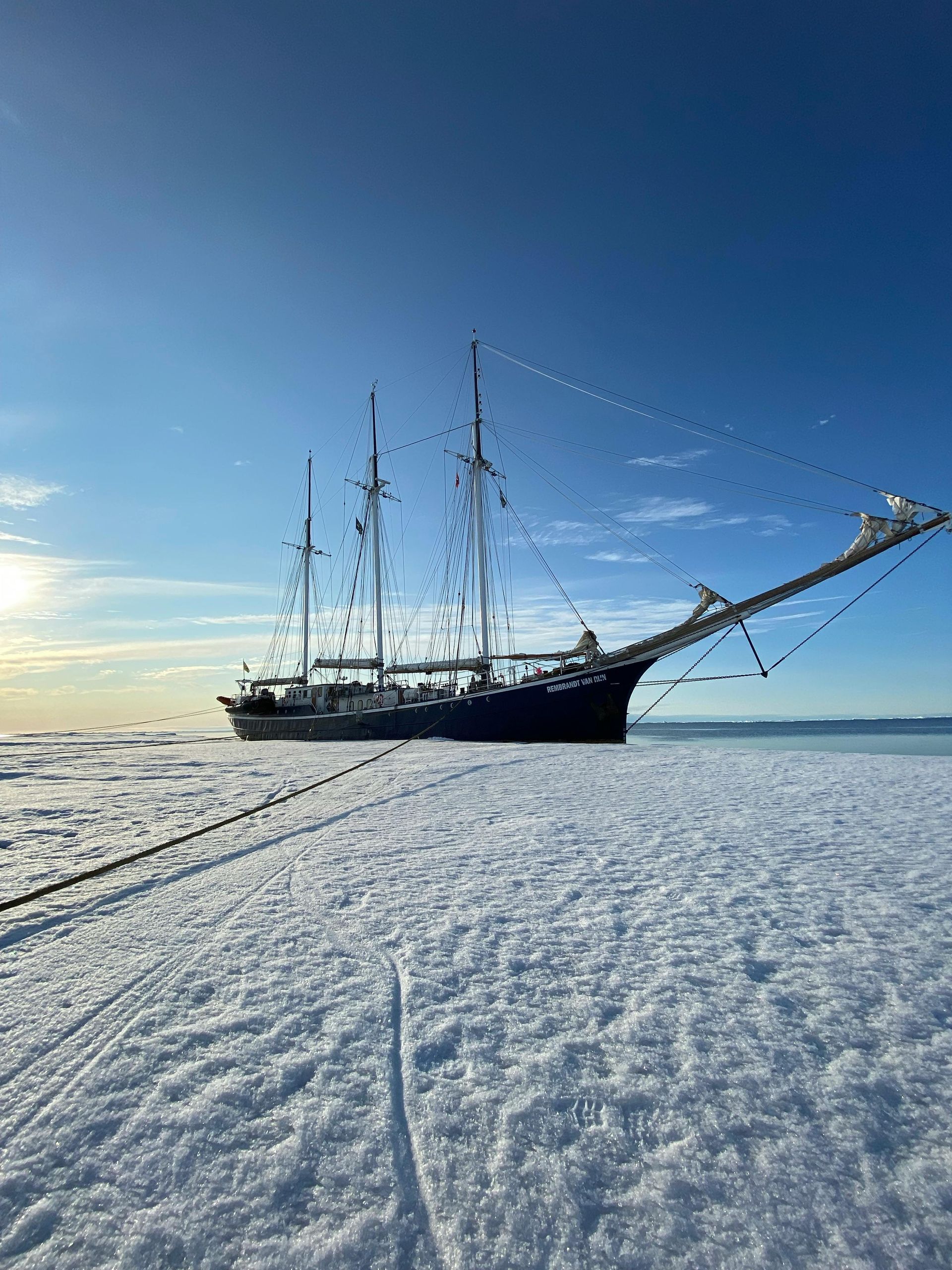 Sailboat frozen in ice, blue sky above.