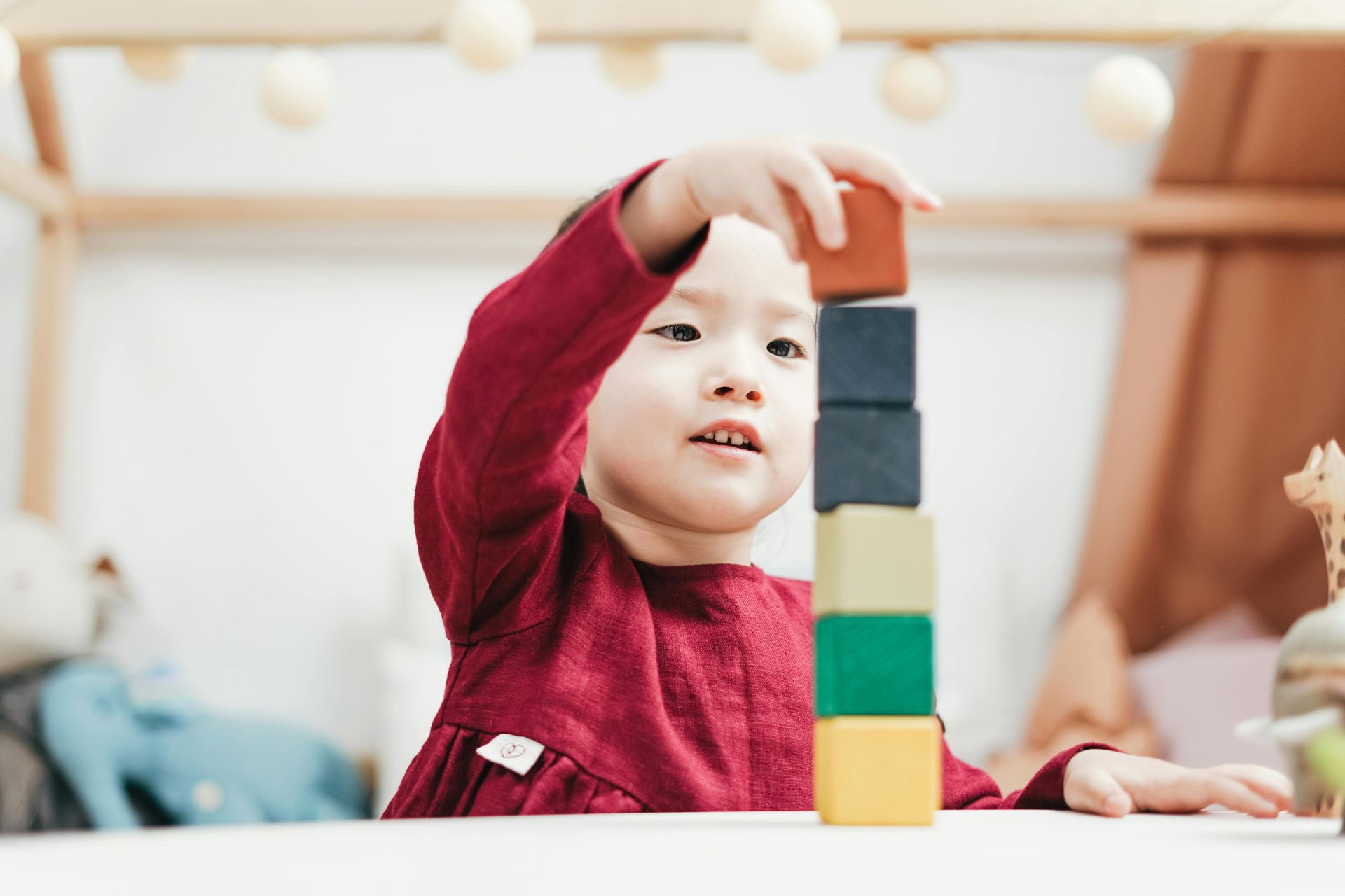 Young child in red shirt stacking colorful blocks.