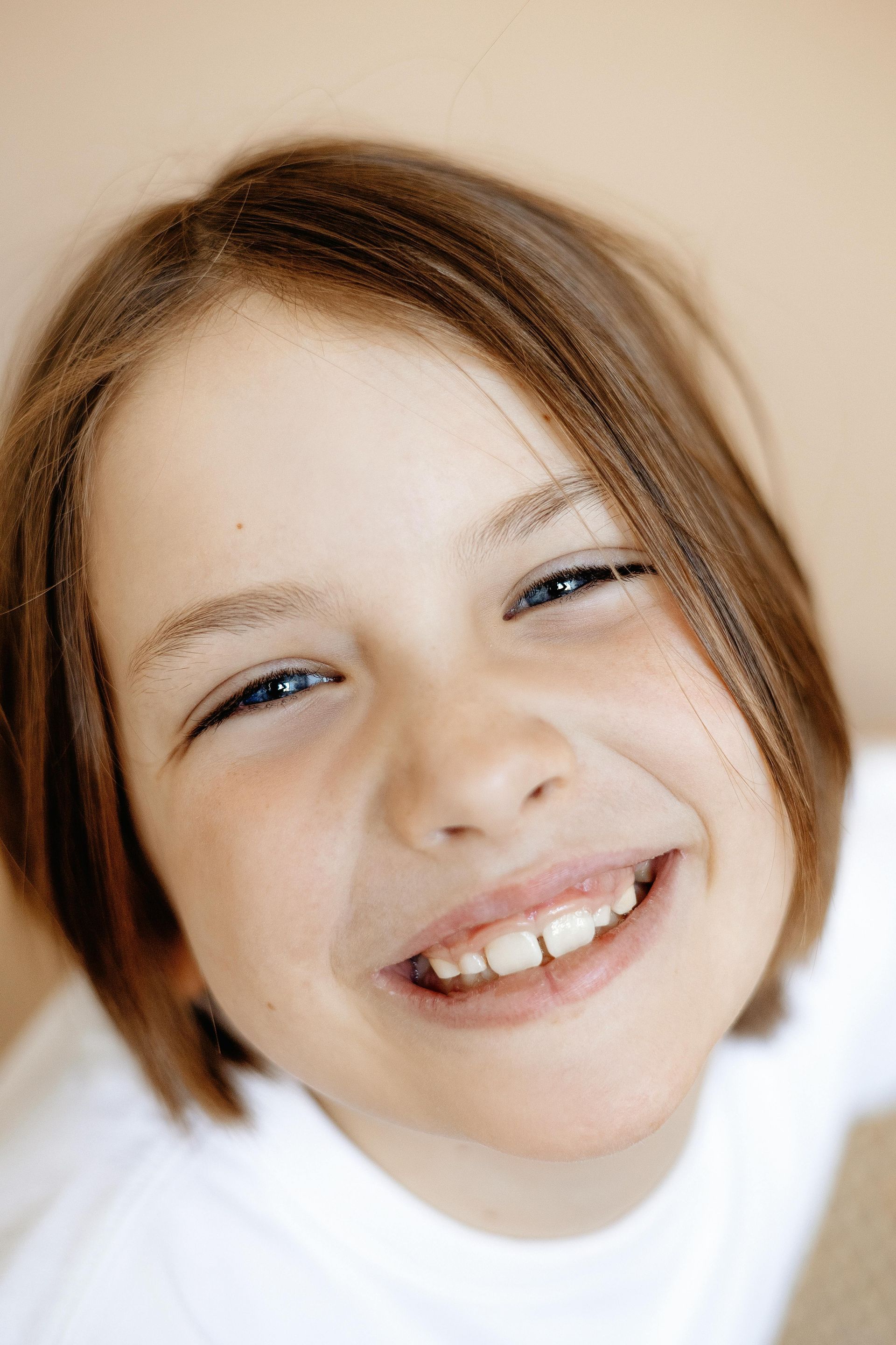 Boy with brown hair smiles broadly.