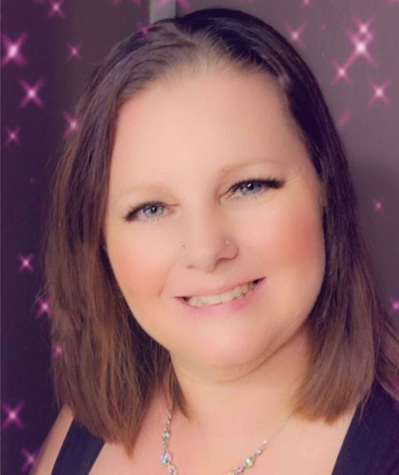 Smiling woman with shoulder-length brown hair against a pink sparkling background