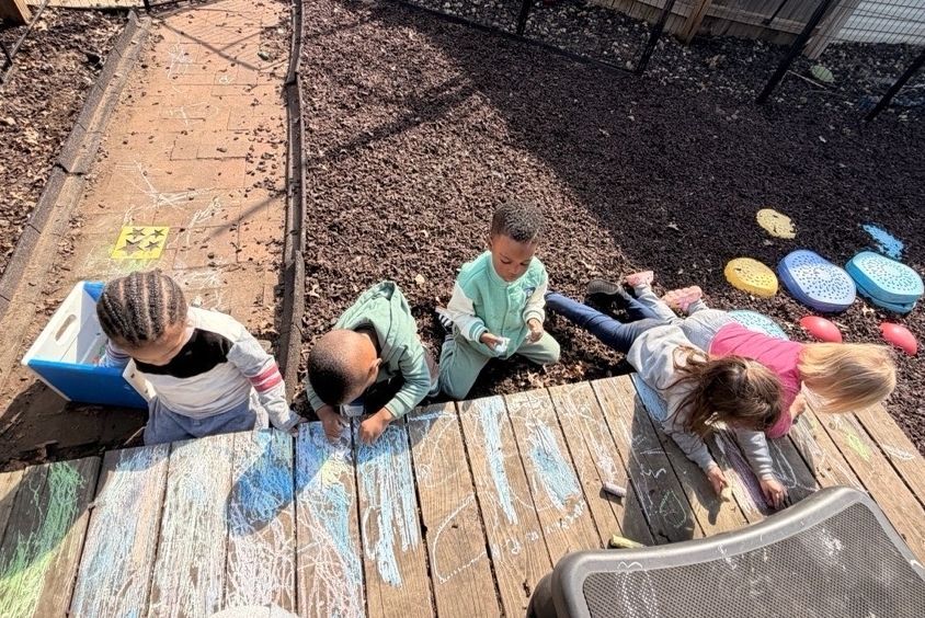 Children climbing up a blue wooden ramp in a gravel playground