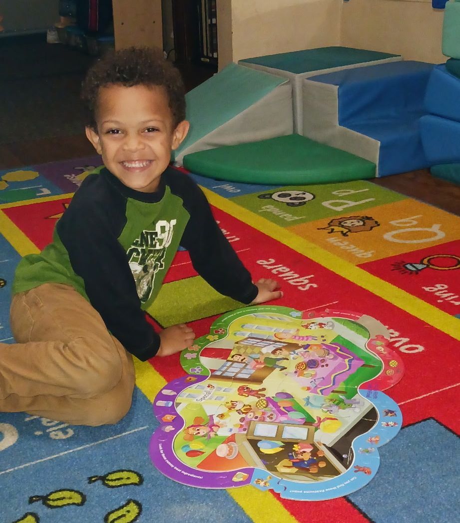Smiling child playing on a colorful puzzle mat indoors