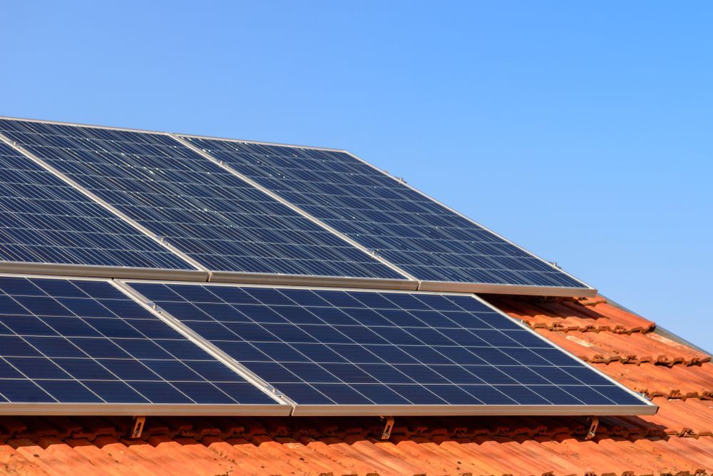 Workers in Blue Coveralls Installing Solar Panels on a Rooftop — Lit Energy in Seaforth, QLD