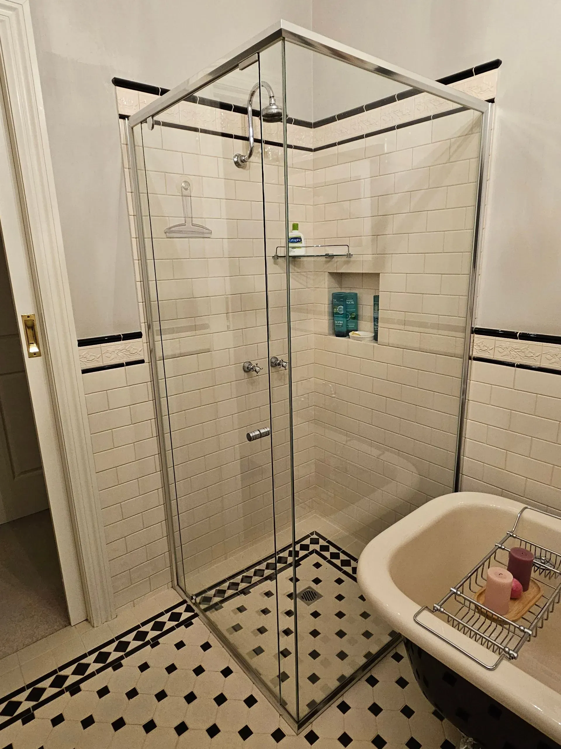 Glass shower enclosure in a bathroom with black-and-white tile and a sink in the foreground