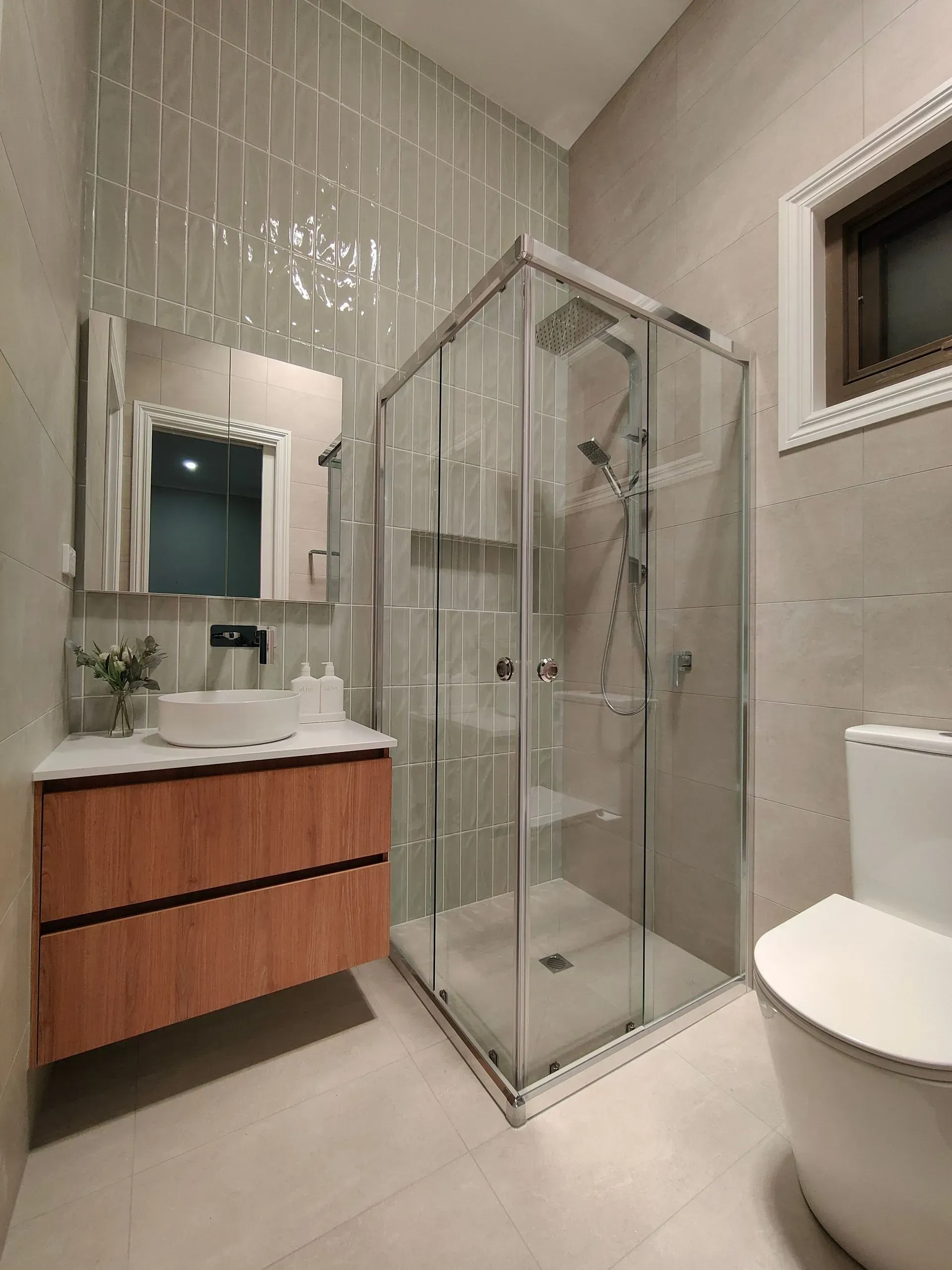 Modern bathroom with glass shower, wood vanity, mirror, and toilet