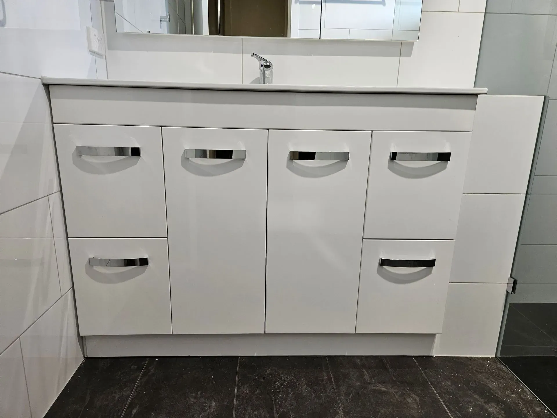 White bathroom vanity with six drawers and cabinets under a sink, viewed from the front.