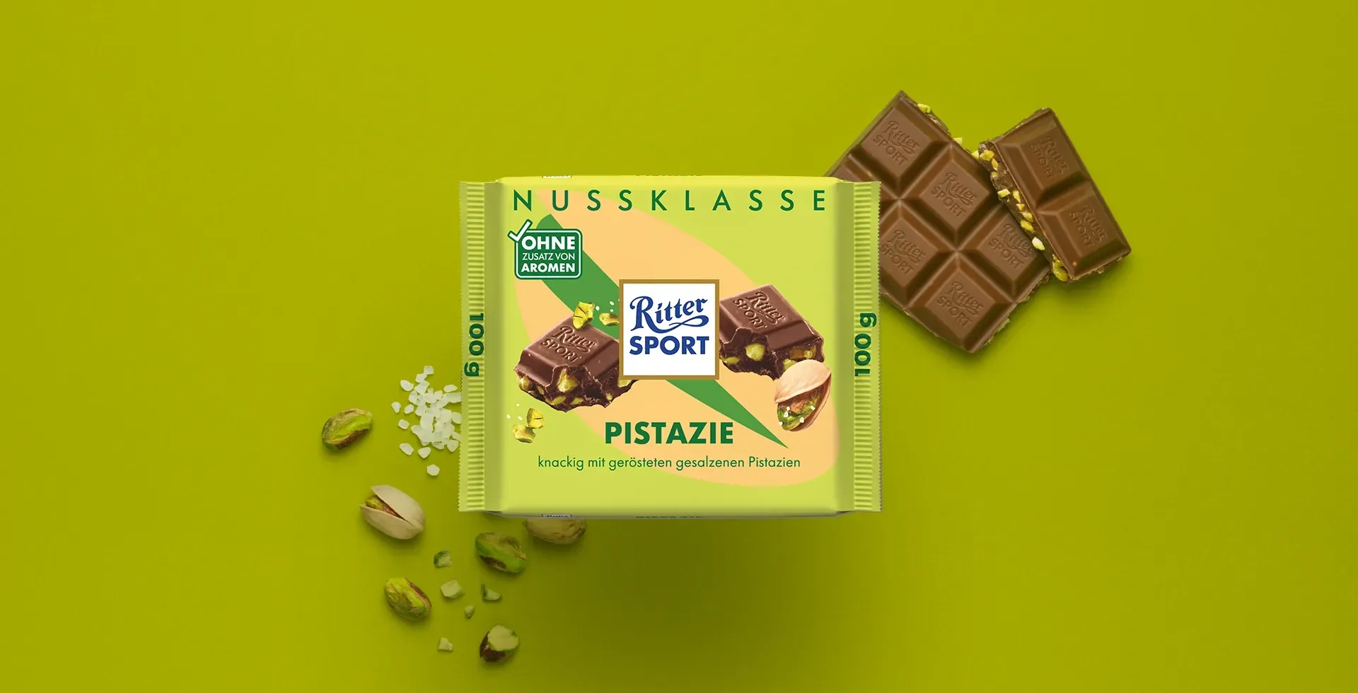 Verpackung einer blauen Schokoladentafel mit Nüssen, Schokoladenstückchen und dem Hinweis „55 % Kakaoanteil“ auf blauem Hintergrund