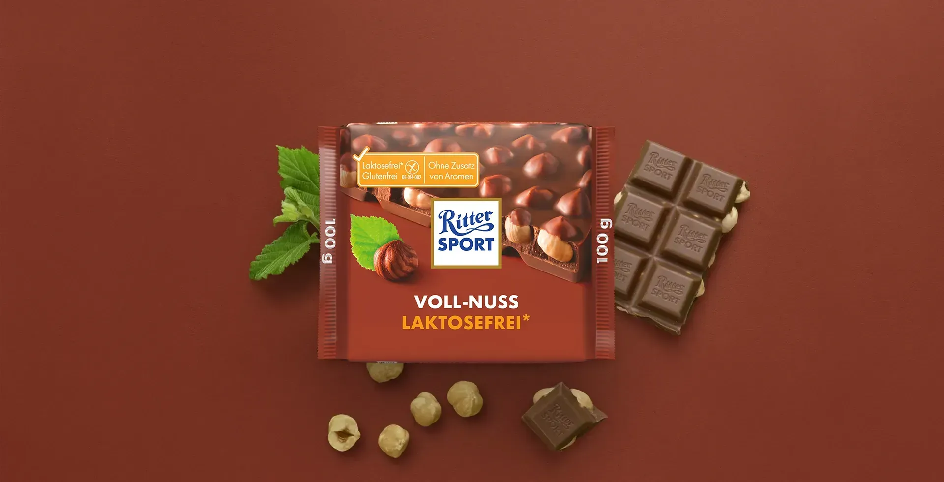 Verpackung einer blauen Schokoladentafel mit Nüssen, Schokoladenstückchen und dem Hinweis „55 % Kakaoanteil“ auf blauem Hintergrund