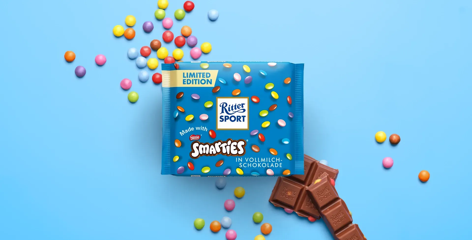 Ritter Sport chocolate bar packaging with cocoa beans, broken chocolate, and milk on a blue background.