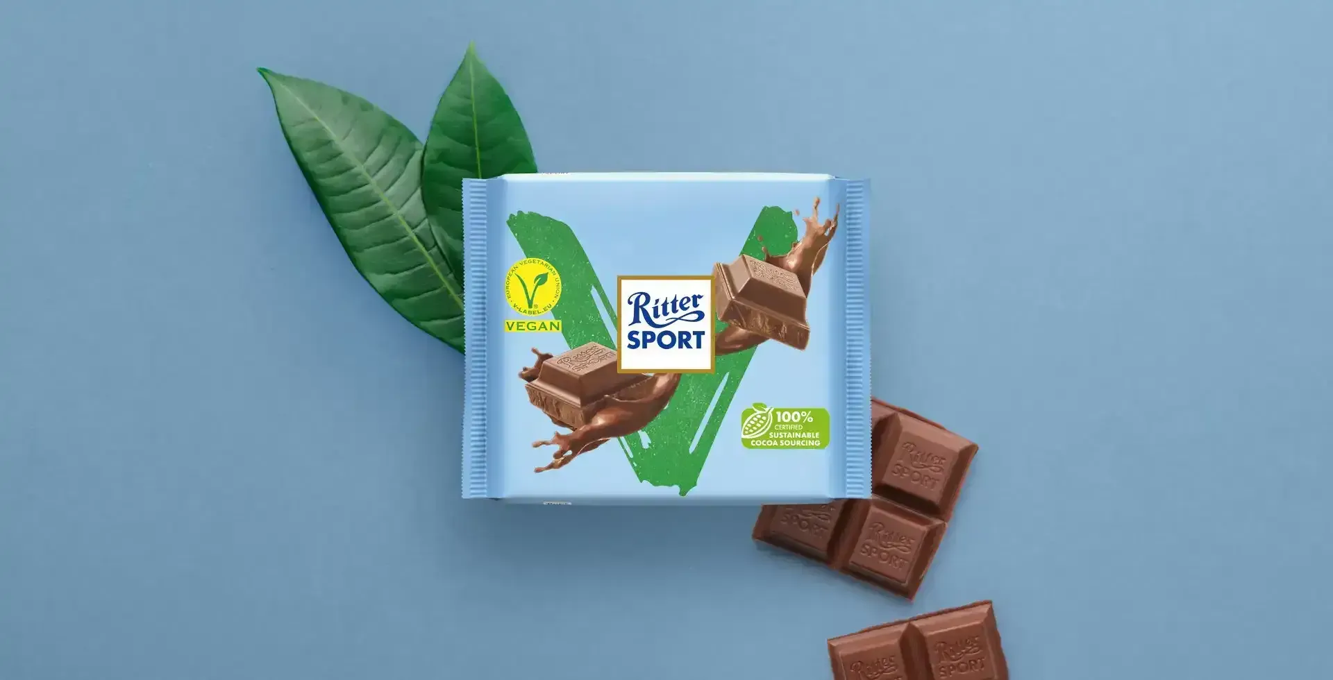 Ritter Sport chocolate bar packaging with cocoa beans, broken chocolate, and milk on a blue background.