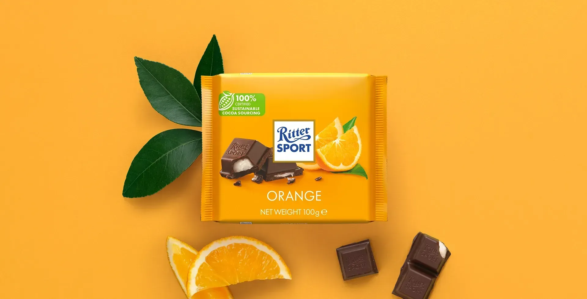 Ritter Sport chocolate bar packaging with cocoa beans, broken chocolate, and milk on a blue background.