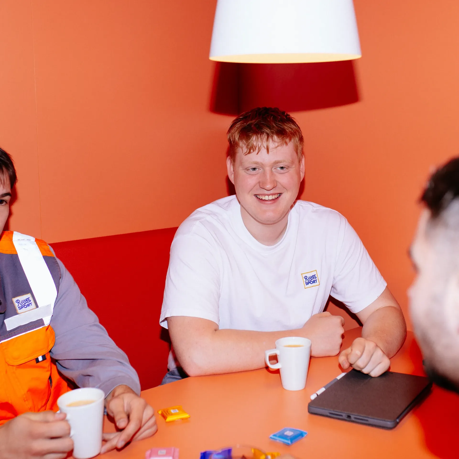 Career Starters Three men are sitting at a table with cups of coffee and a laptop
