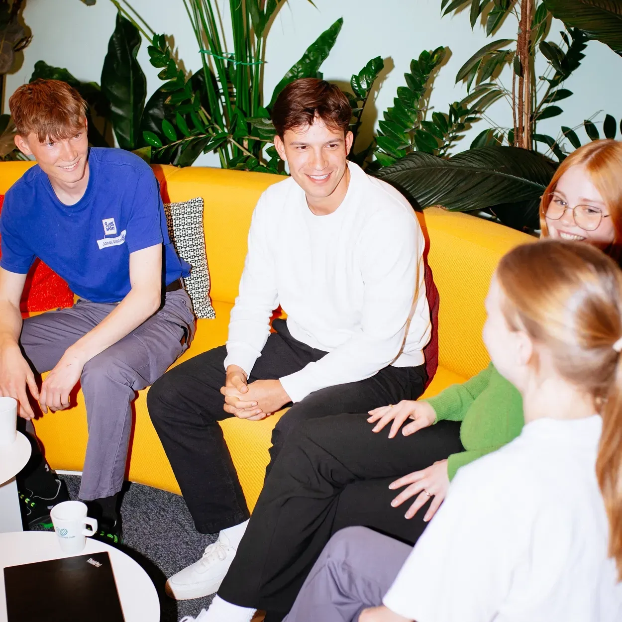 A group of young people are sitting on a yellow couch
