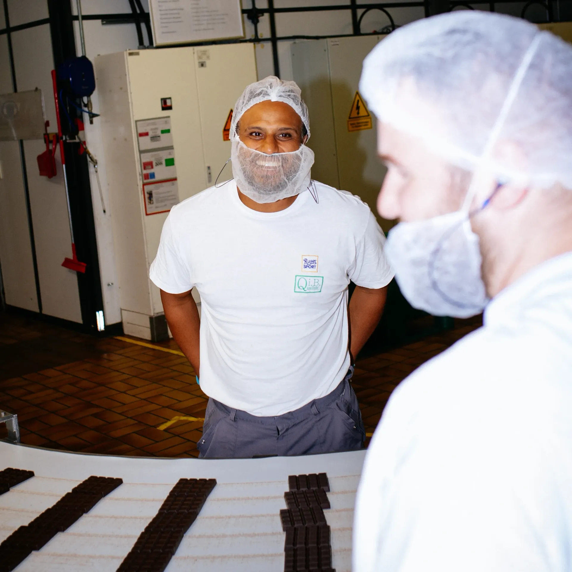A man with a beard wearing a white shirt that says Ritter Sport on it