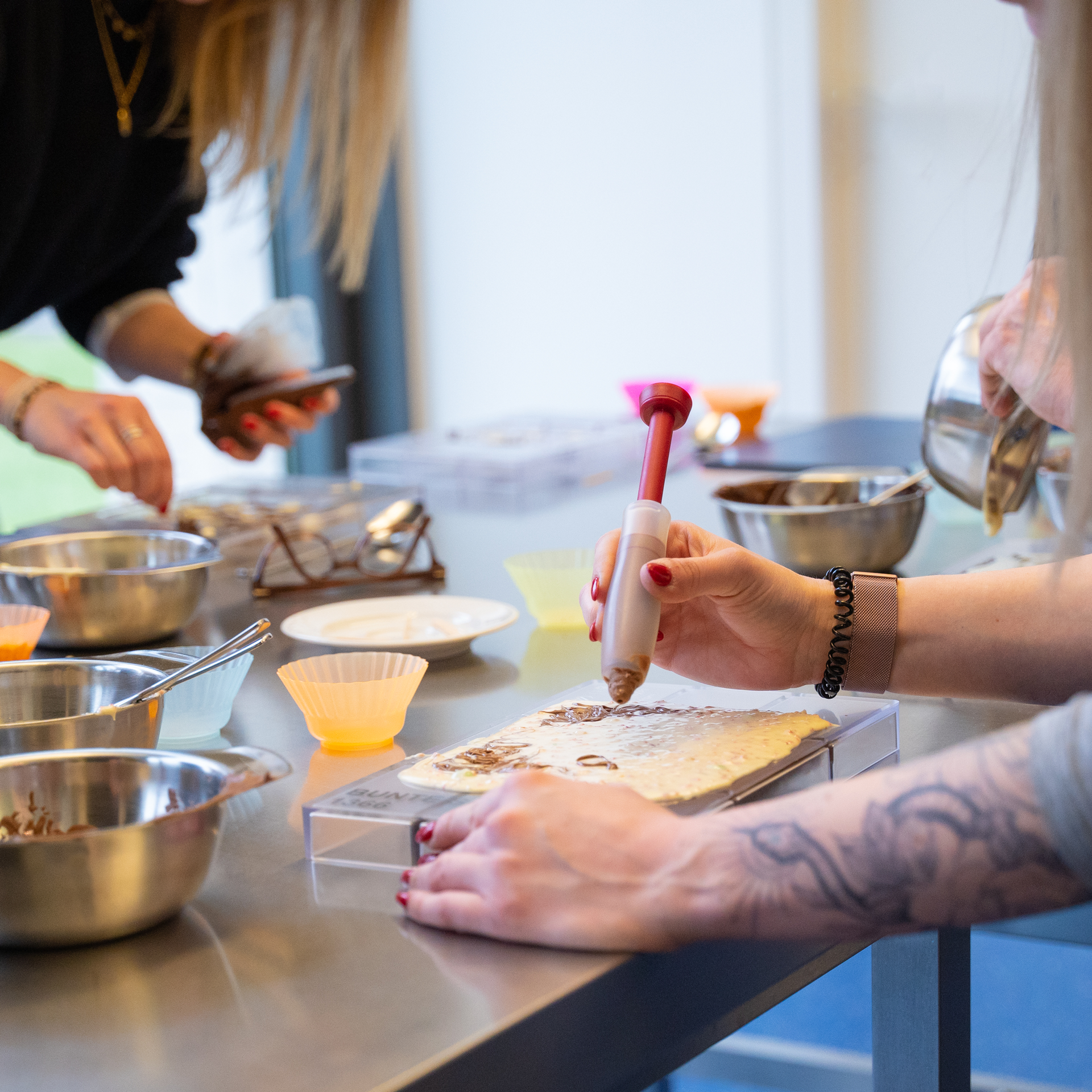 Eine Person mit einem Tattoo auf dem Arm dekoriert einen Kuchen