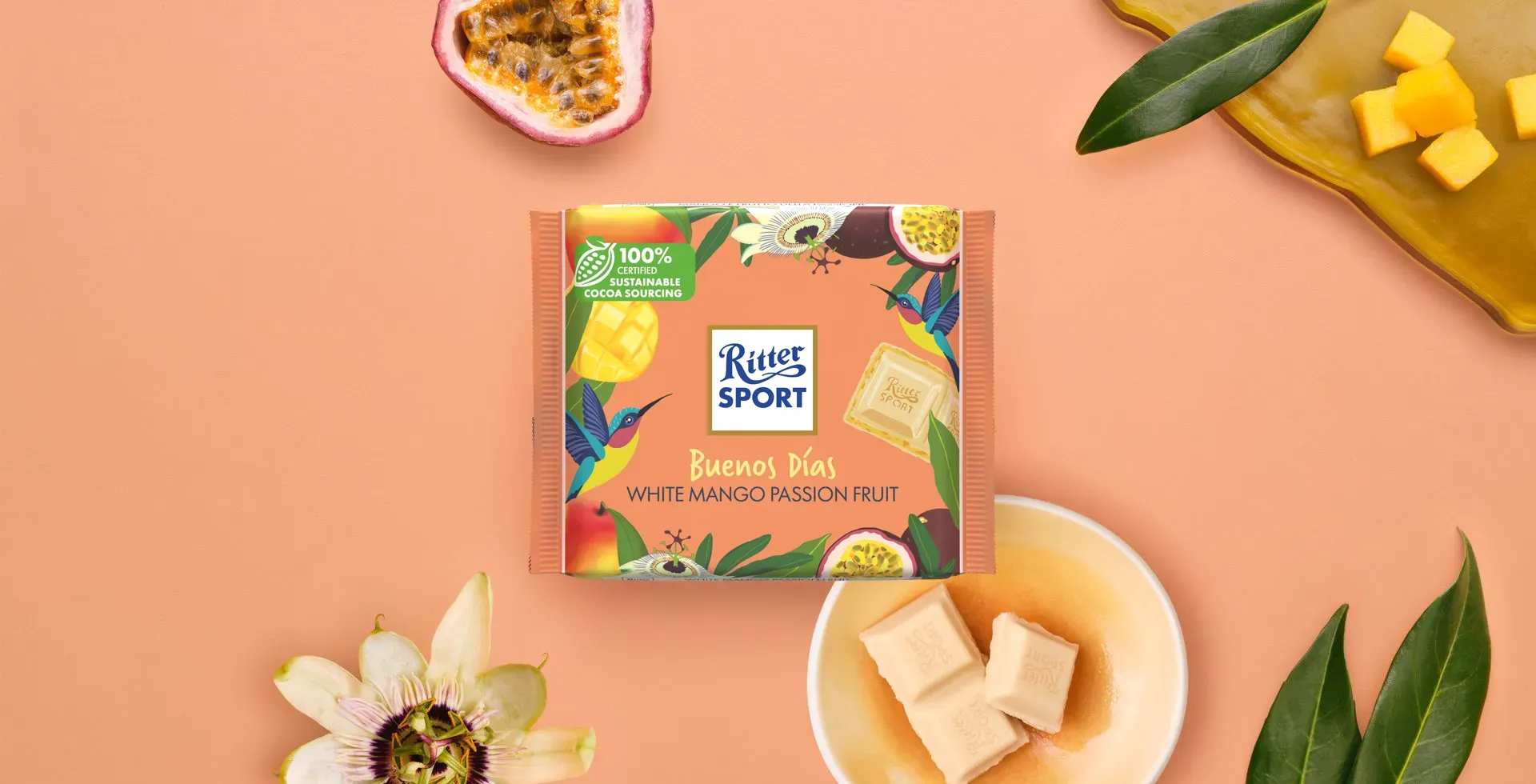 Ritter Sport chocolate bar packaging with cocoa beans, broken chocolate, and milk on a blue background.