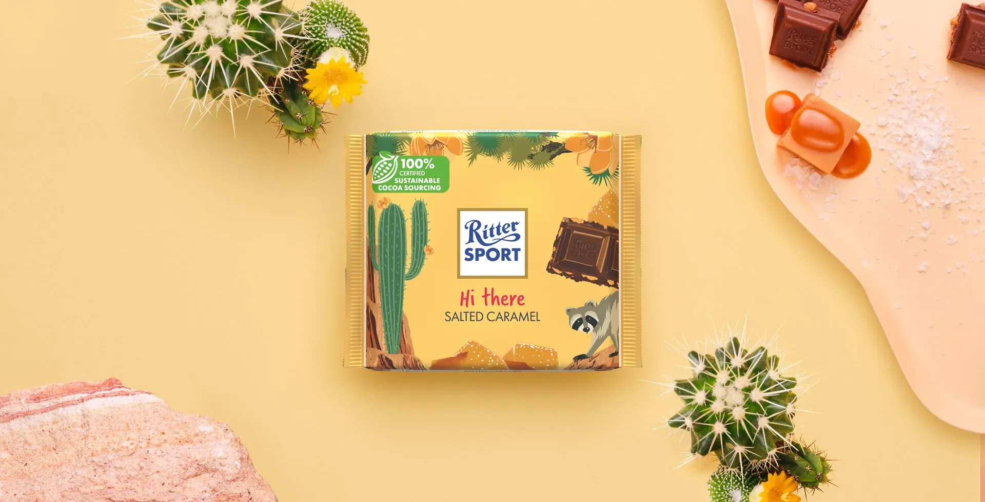 Ritter Sport chocolate bar packaging with cocoa beans, broken chocolate, and milk on a blue background.