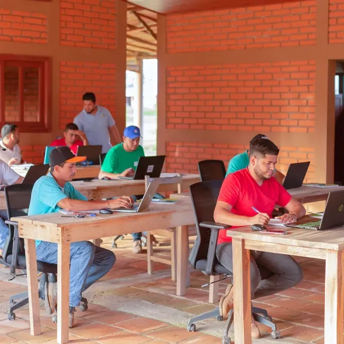 A group of people are sitting at tables with laptops.
