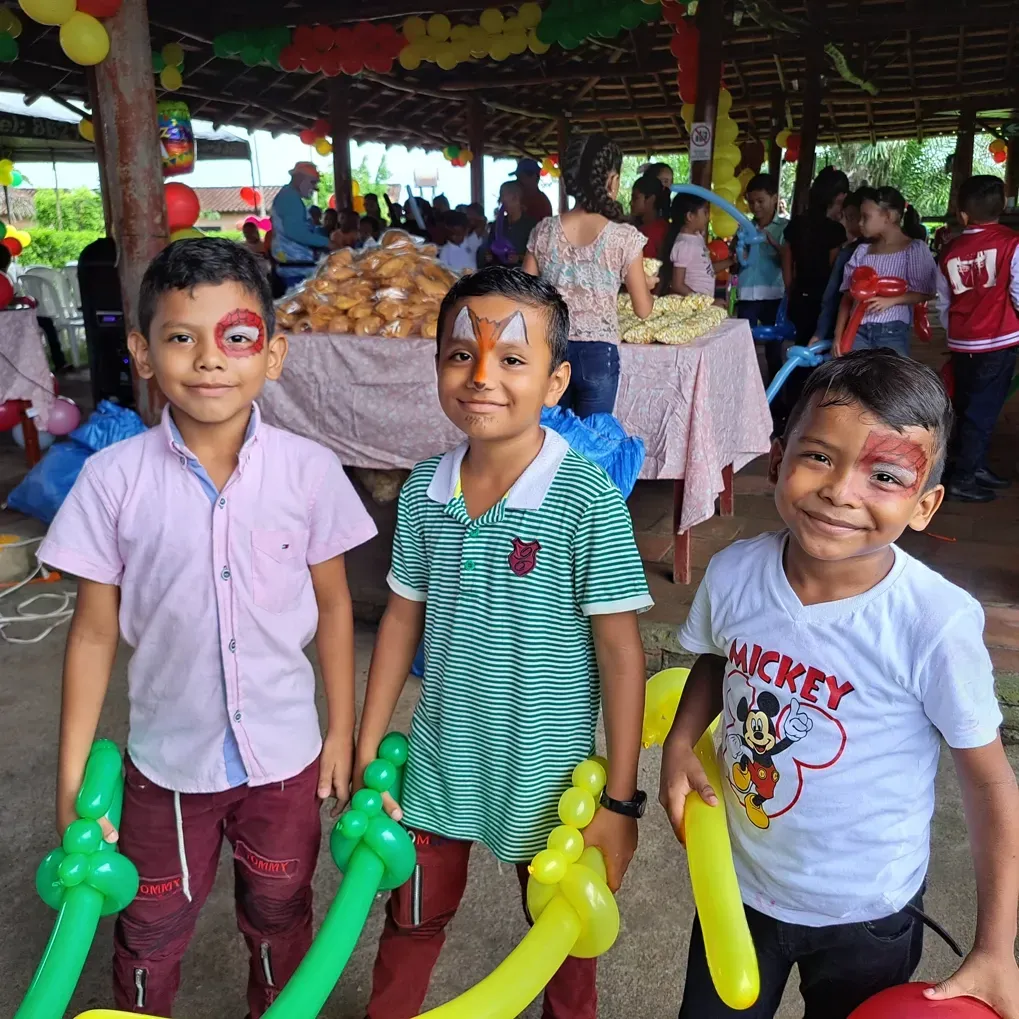 A boy wearing a mickey mouse shirt is holding balloons