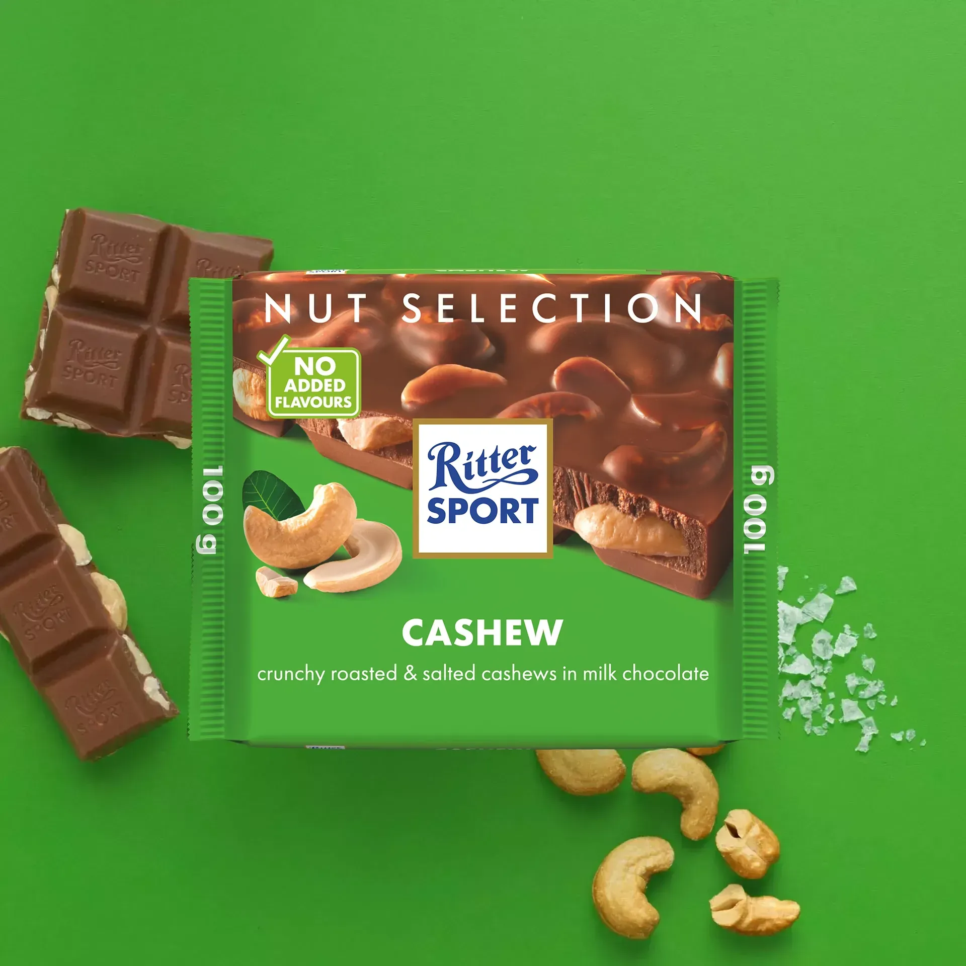 Ritter Sport Cashew chocolate bar with scattered cashews, chocolate pieces, and a green background.