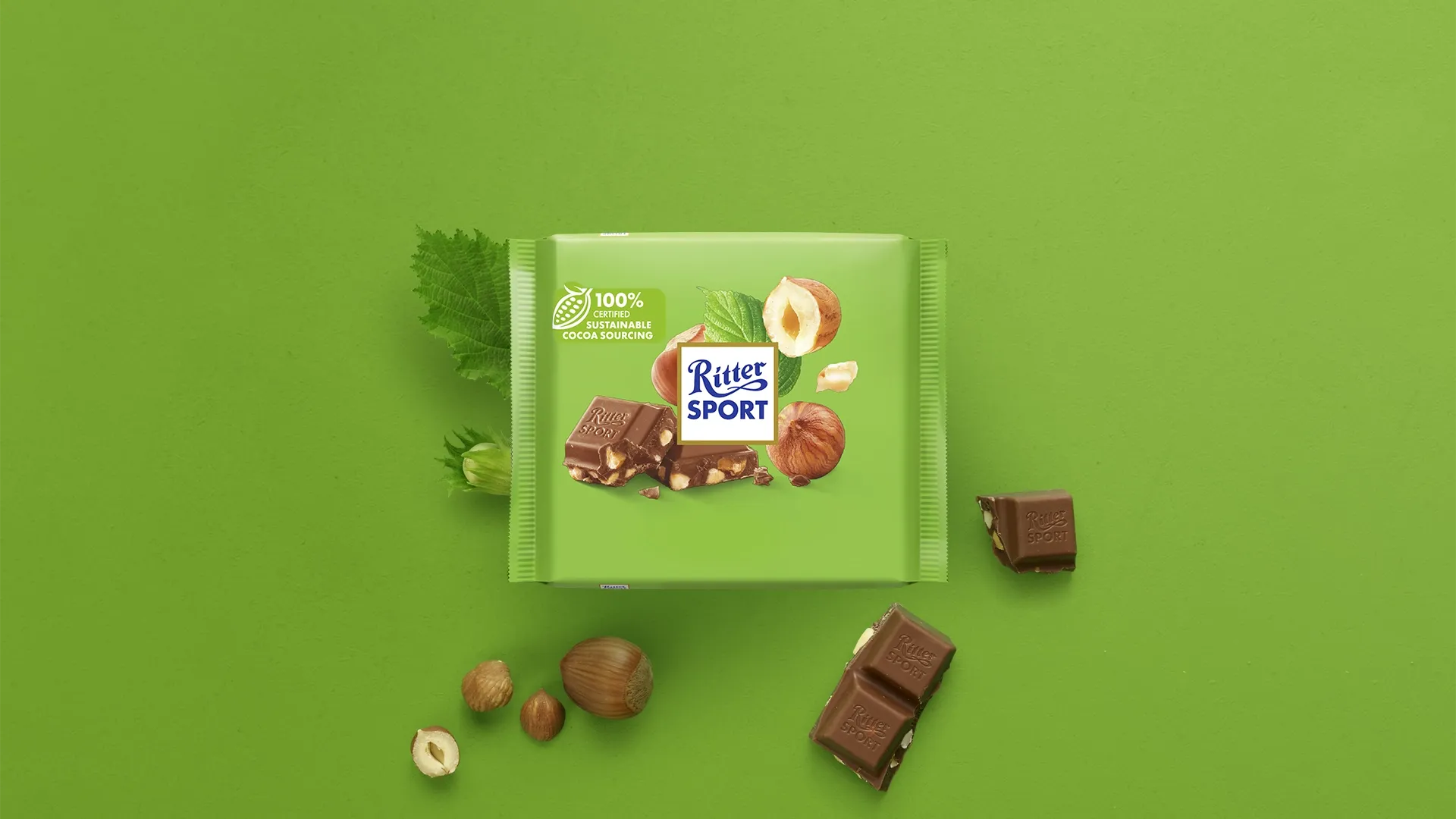 Ritter Sport chocolate bar packaging with cocoa beans, broken chocolate, and milk on a blue background.