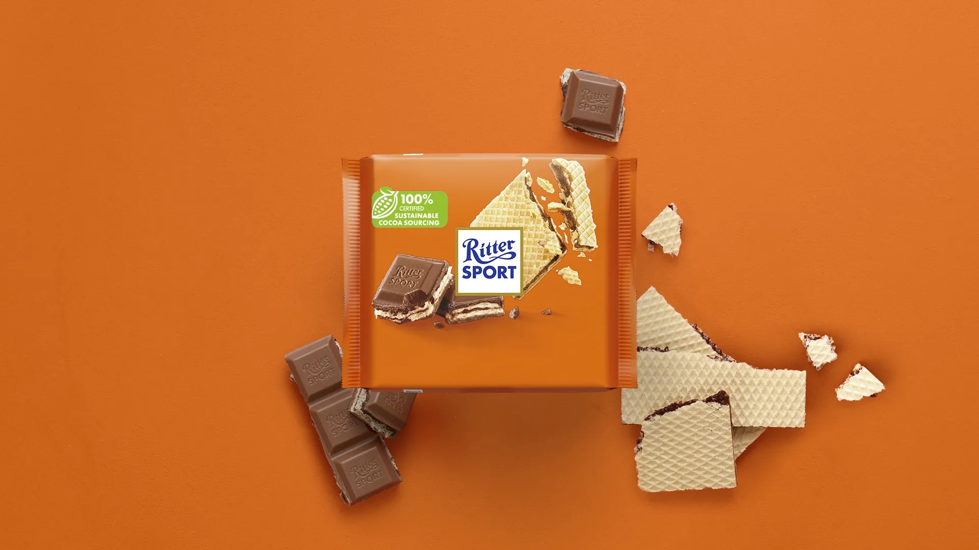 Ritter Sport chocolate bar packaging with cocoa beans, broken chocolate, and milk on a blue background.