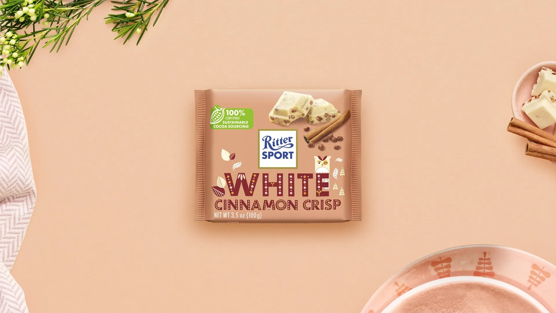 Ritter Sport chocolate bar packaging with cocoa beans, broken chocolate, and milk on a blue background.