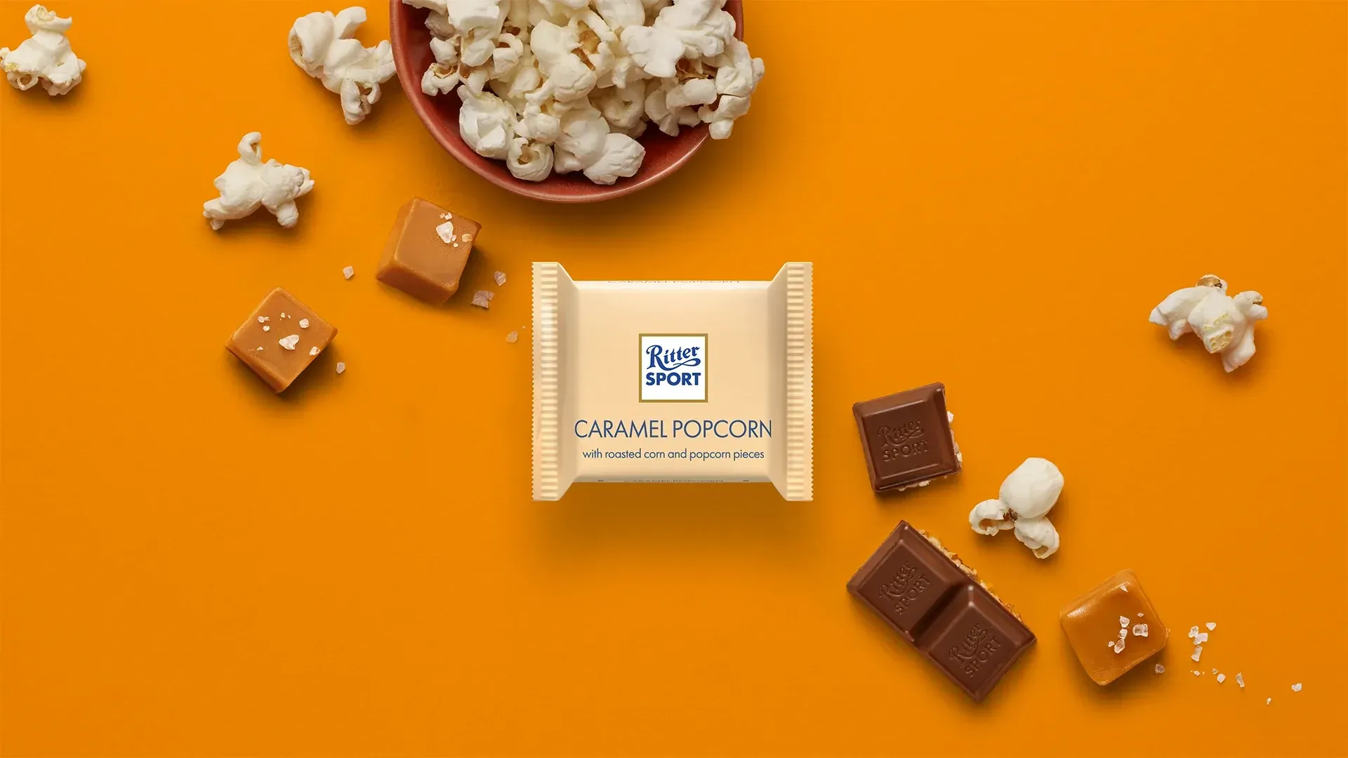 Ritter Sport chocolate bar packaging with cocoa beans, broken chocolate, and milk on a blue background.