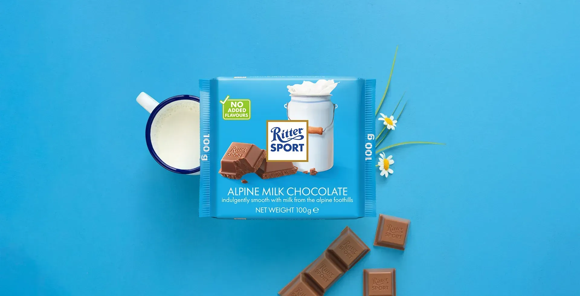 Ritter Sport chocolate bar packaging with cocoa beans, broken chocolate, and milk on a blue background.