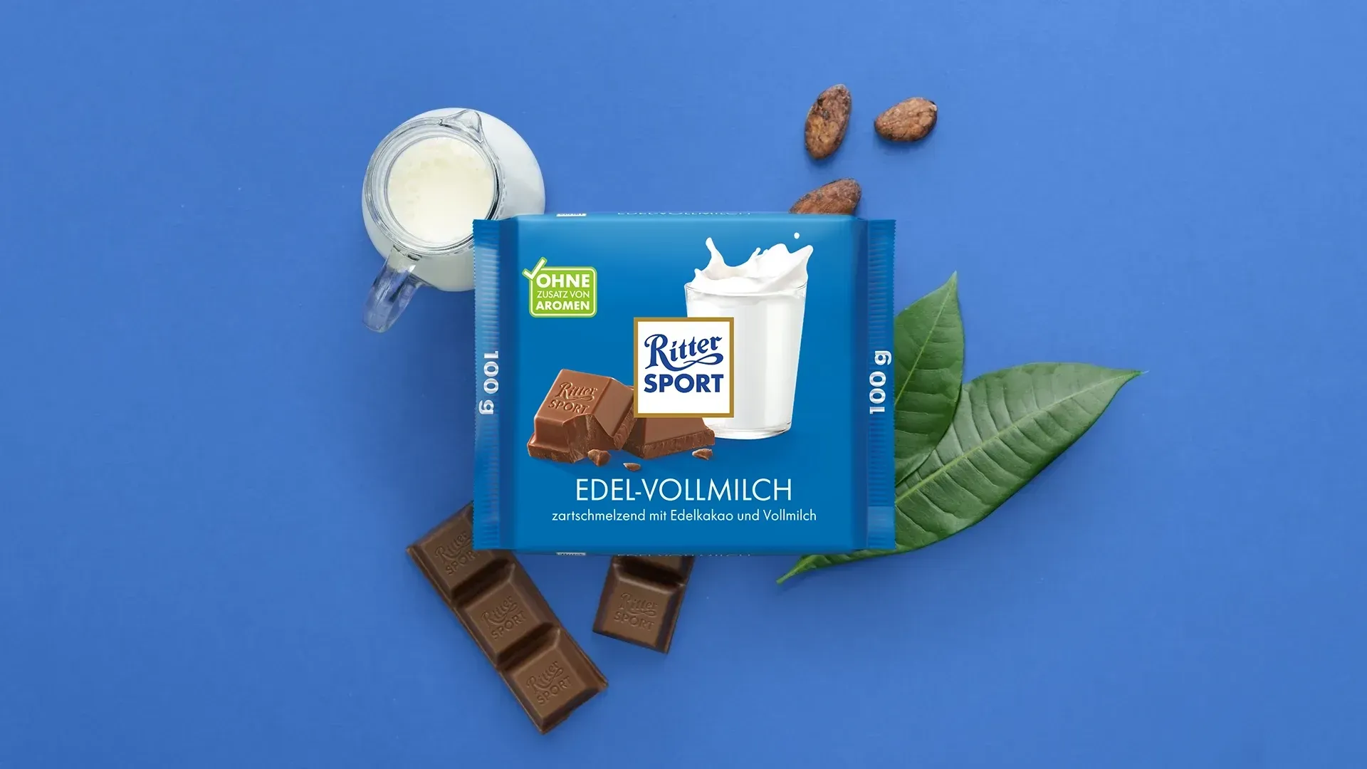 Verpackung einer blauen Schokoladentafel mit Nüssen, Schokoladenstückchen und dem Hinweis „55 % Kakaoanteil“ auf blauem Hintergrund