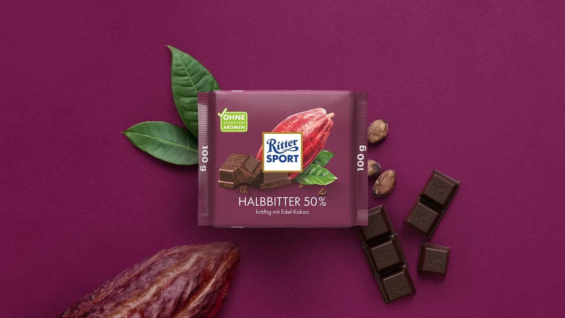 Verpackung einer blauen Schokoladentafel mit Nüssen, Schokoladenstückchen und dem Hinweis „55 % Kakaoanteil“ auf blauem Hintergrund