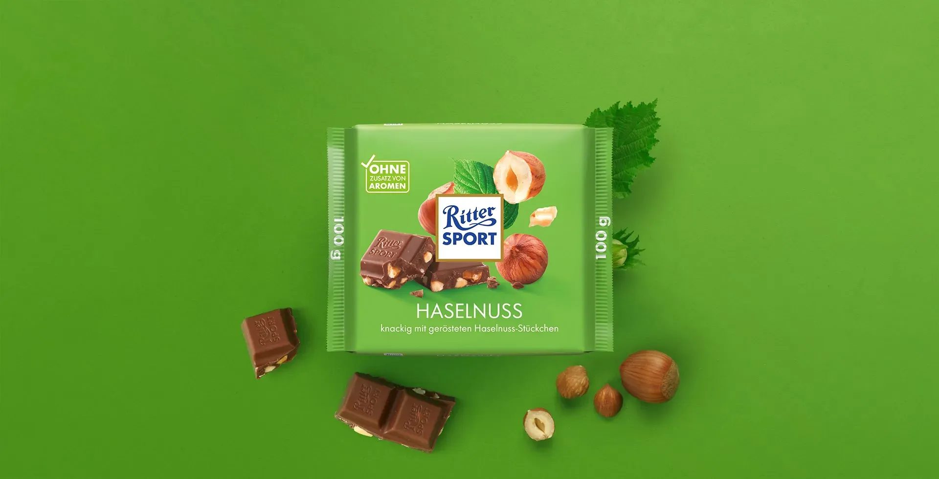 Verpackung einer blauen Schokoladentafel mit Nüssen, Schokoladenstückchen und dem Hinweis „55 % Kakaoanteil“ auf blauem Hintergrund