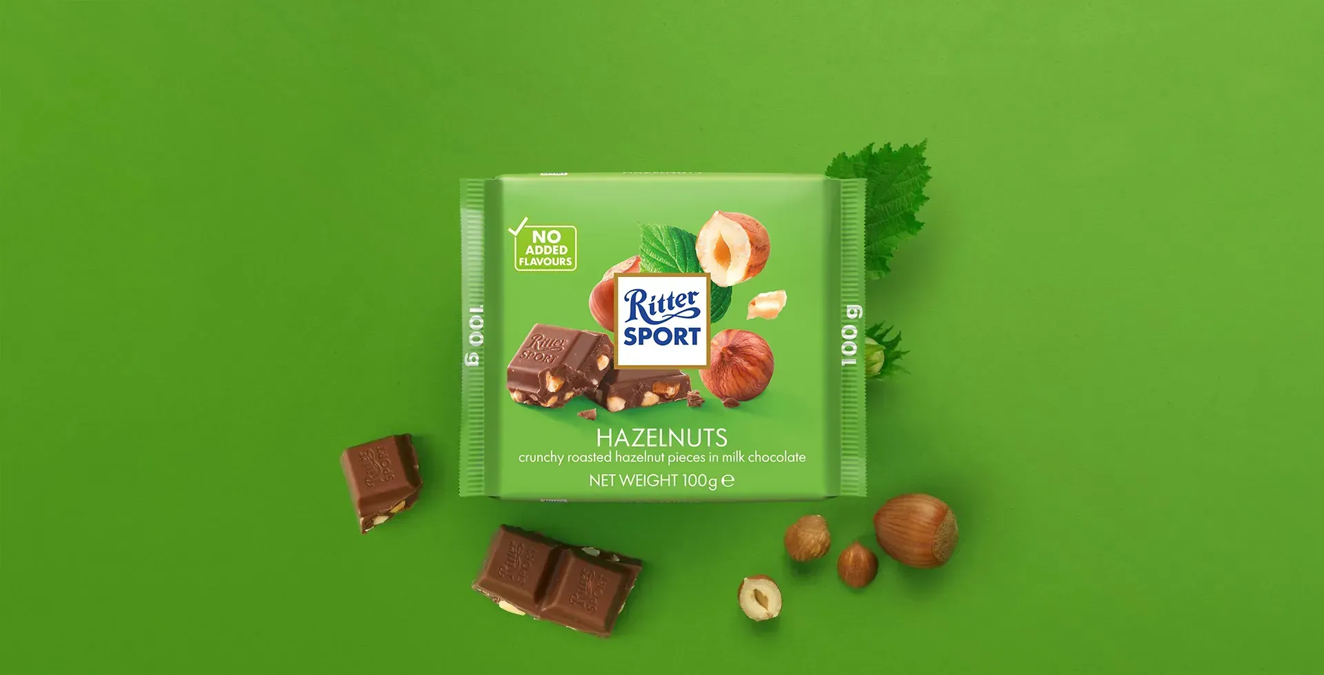 Ritter Sport chocolate bar packaging with cocoa beans, broken chocolate, and milk on a blue background.