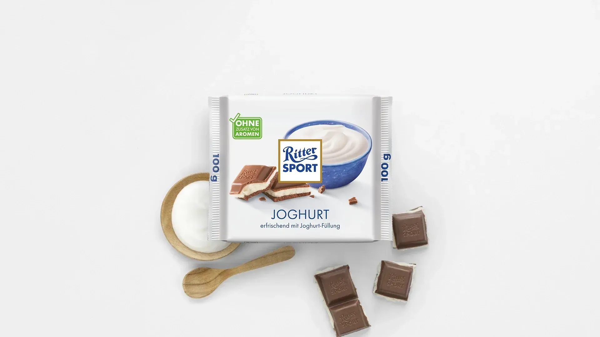 Verpackung einer blauen Schokoladentafel mit Nüssen, Schokoladenstückchen und dem Hinweis „55 % Kakaoanteil“ auf blauem Hintergrund