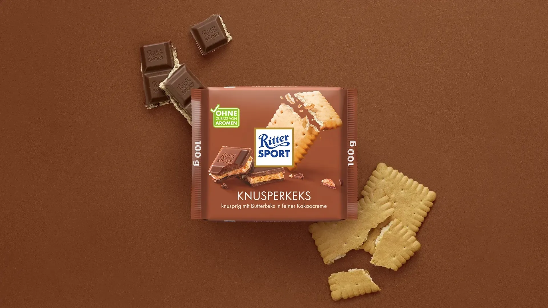 Verpackung einer blauen Schokoladentafel mit Nüssen, Schokoladenstückchen und dem Hinweis „55 % Kakaoanteil“ auf blauem Hintergrund