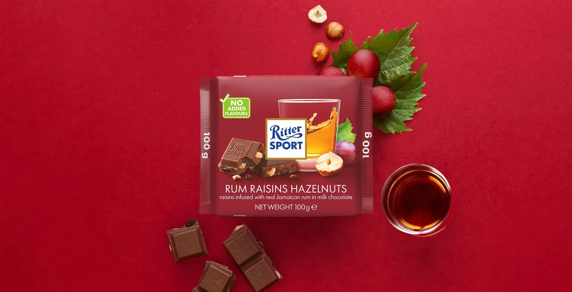 Ritter Sport chocolate bar packaging with cocoa beans, broken chocolate, and milk on a blue background.