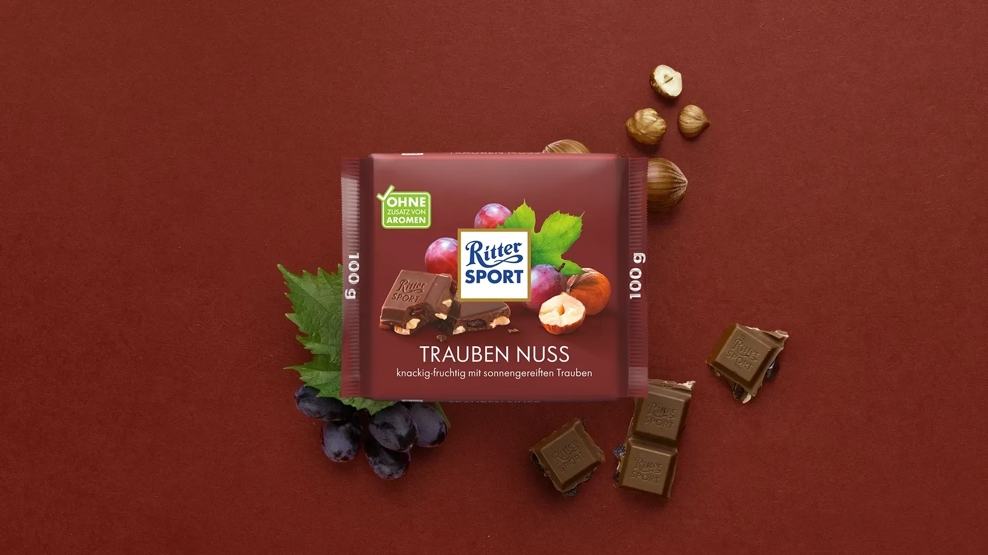 Verpackung einer blauen Schokoladentafel mit Nüssen, Schokoladenstückchen und dem Hinweis „55 % Kakaoanteil“ auf blauem Hintergrund