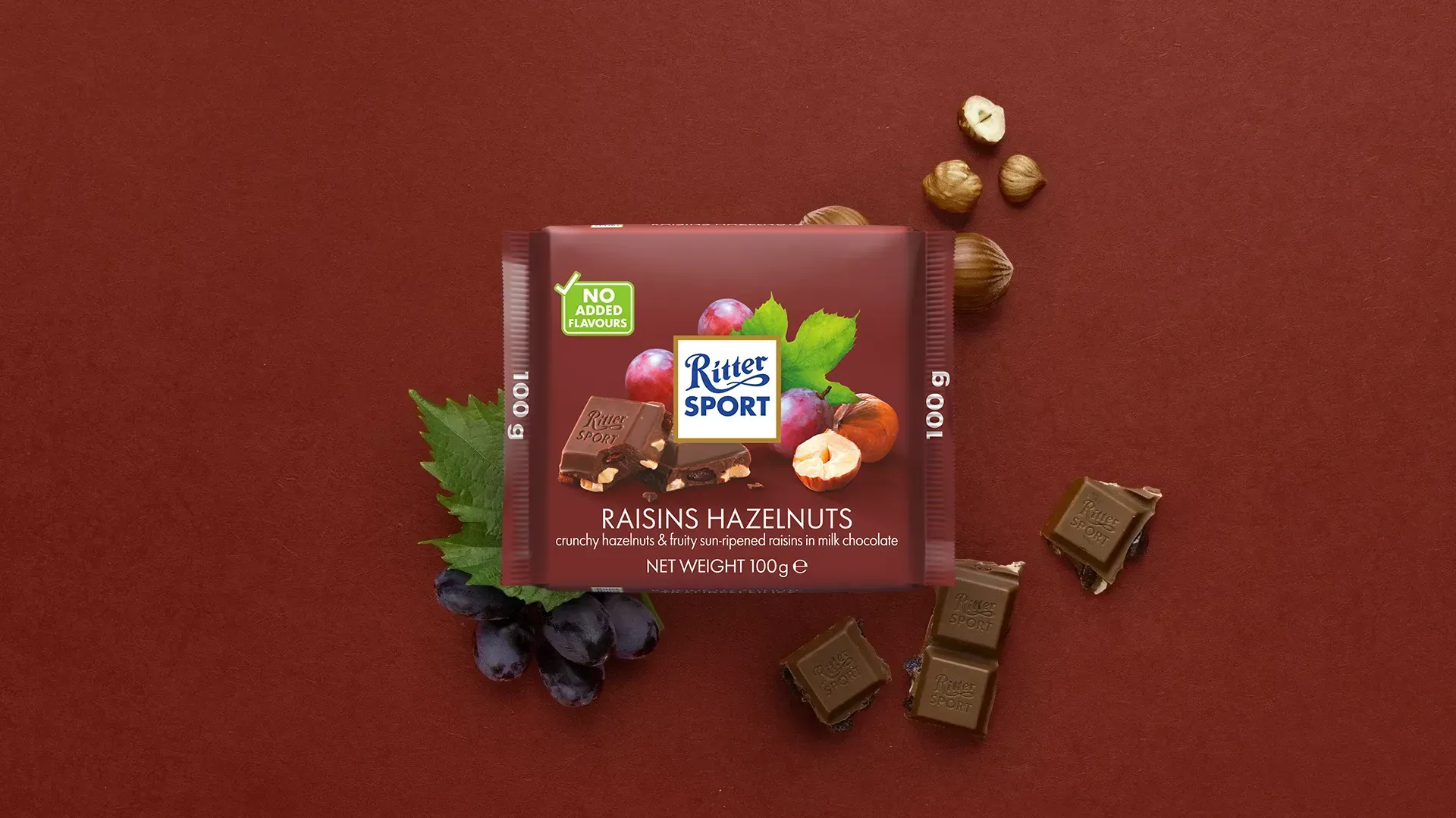 Ritter Sport chocolate bar packaging with cocoa beans, broken chocolate, and milk on a blue background.